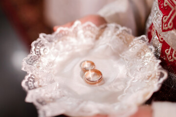 Wedding ceremony in church. Priest holding plate with stylish wedding rings in church for holy matrimony. Wedding rings for bride and groom