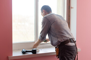 The worker installing and checking window in the house