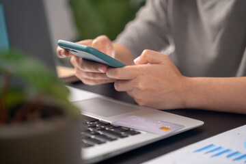 Close up shot of females hands typing on smart phone at home offeice.