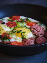 Fried eggs with smoked sausage in a frying pan.