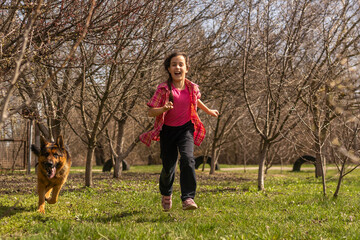 little girl running fast with a shepherd in the park