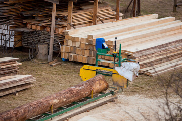 Fototapeta premium Sawmill. Process of machining logs in equipment sawmill. Machine saw saws the tree trunk on the plank boards. Wood sawdust work sawing timber wood.