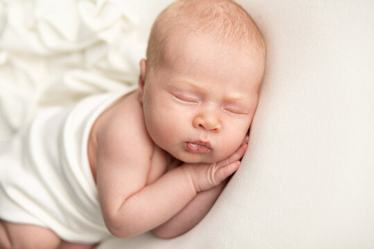 Newborn baby sleeping on a white blanket
