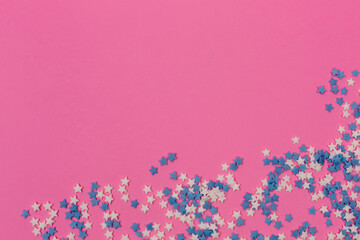 Festive frame made of colorful pastel sprinkles on a pink background, copy space on top. Sprinkle...