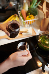 Closeup image of man putting spoon of ground coffee in moka pot