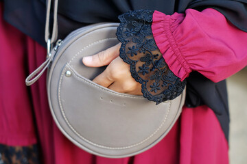 Closeup of a woman holding a sling bag on gray