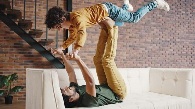 Father and stepson perform acrobatic stunt on sofa at home