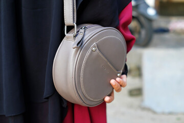 Closeup of a woman holding a sling bag on gray