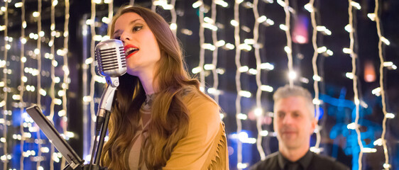 Woman singer singing in her band on the concert stage