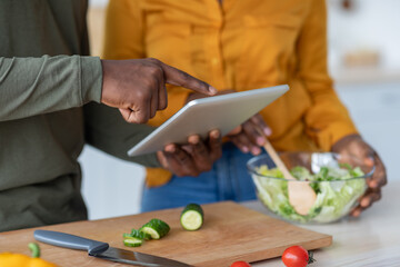 Obraz premium Black Man And Woman Using Digital Tablet While Cooking Lunch In Kitchen