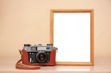 Camera and photo frame on table and neutral background