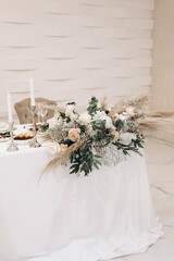 Luxury wedding table decor in white shades. White roses, set and candles