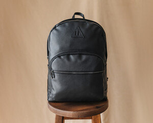 Black stylish leather backpack on a beige background. Classic accessories for business. Bag for...