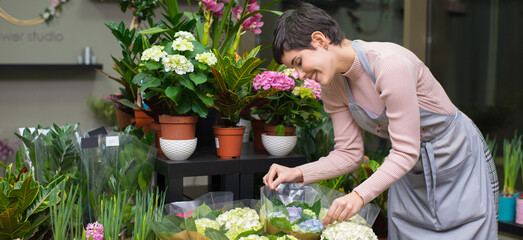 Young woman professional florist working with flowers in her flower shop