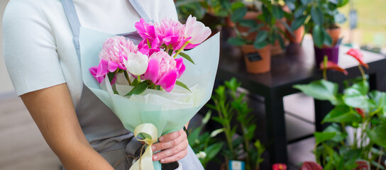 Young woman professional florist working with flowers in her flower shop