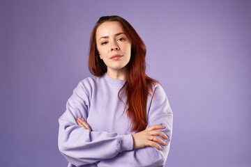 Caucasian woman in violet sweatshirt. Natural look. Smiling. long red hair. White background