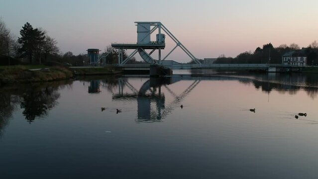 Coucher de soleil sur le rivi&egrave;re derri&egrave;re un pont avec des canards qui nagent