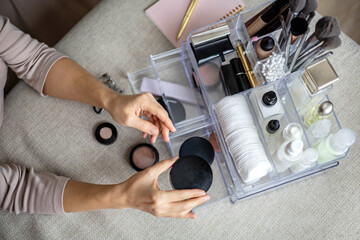 Closeup female hands putting luxury cosmetic into acrylic box with drawer storage organization