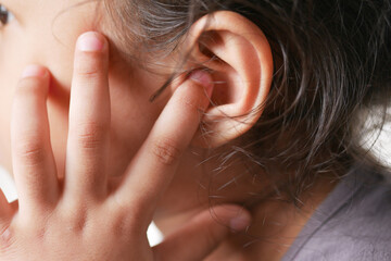  child girl having ear pain touching his painful ear ,