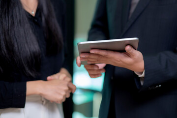 Closeup hands of business team man and woman standing and talking about marketing on tablet with social network at the office, secretary report with executive for planning marketing, business concept.