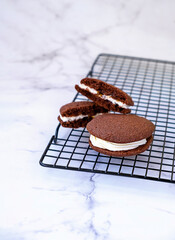Homemade chocolate sandwich cookies. Light marble background.