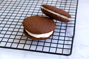 Homemade chocolate sandwich cookies. Light marble background.