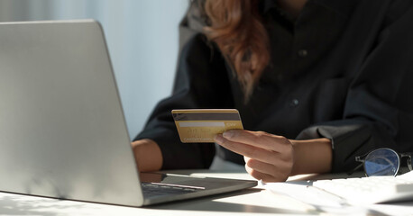 Asian woman checking online order details on computer and use the credit card information entered on the computer.