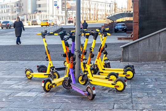 Bright electric scooters parked at the pole