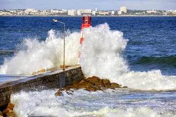 Fototapeta na wymiar huge wave crashing over Lagos lighthouse and pier, Algarve, Portugal