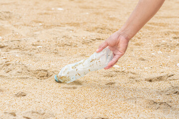 Woman cleans up by picking up plastic bottles at beach. Concept of protecting the environment, saving the world, recycling, reducing global warming. closeup, blurred background, World Environment Day