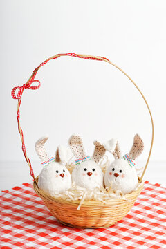 Three handmade Easter bunnies in a wicker basket against white background