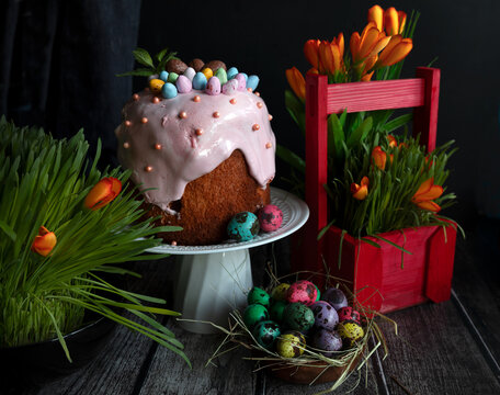 Traditional Easter cake and painted eggs on a wooden table. Easter pastries.