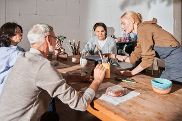 Woman involved at the pottery master class while teaching her group of mature people