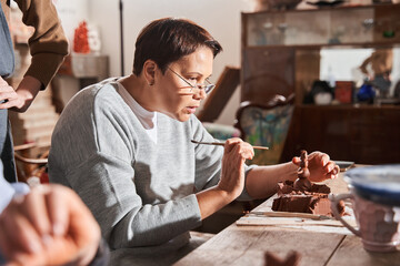 ature woman making interesting shape from the clay with special stick at the hand