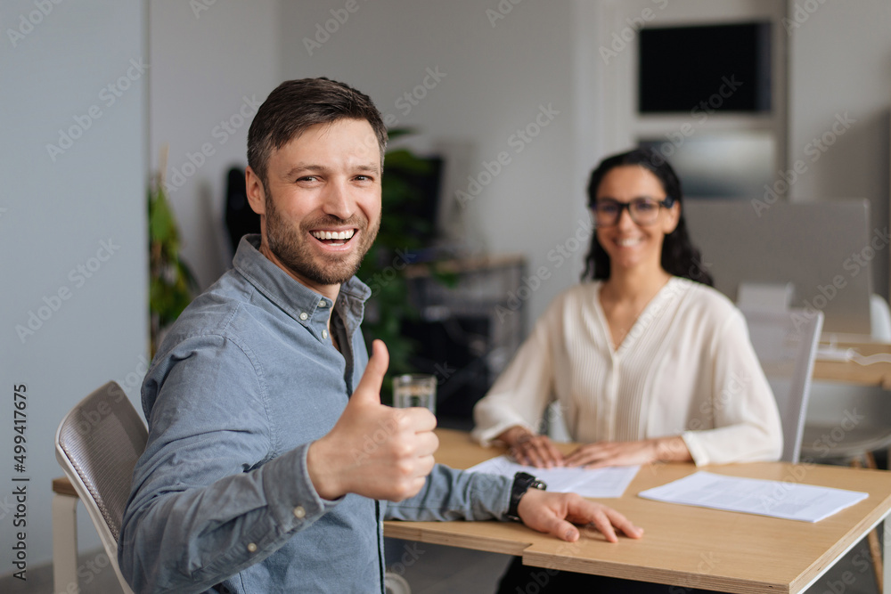 Poster successful work interview. happy young caucasian guy showing thumb up gesture after speaking to hiri