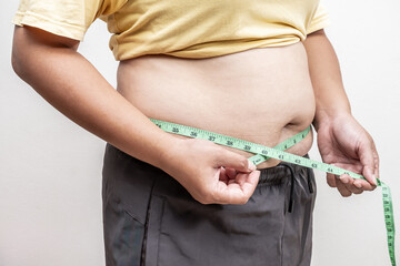 Fat asia girl with overweight checking out his weight, hand holding measurement tape on her belly fat.woman diet lifestyle and build muscle concept.