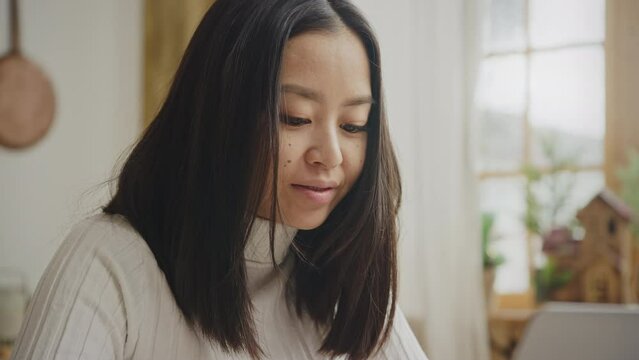 Close up portrait of a young adult asian woman with braces smiling while working on a laptop