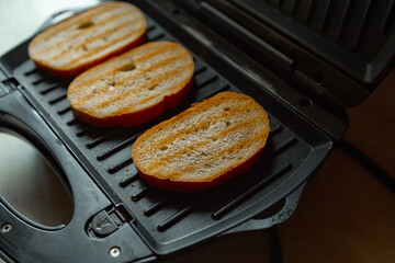 Three grilled bakery slices. Toast bread pan fried on black electric kitchen grill. Morning breakfast cooking of crunchy homemade snack.