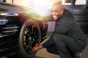 Professional service with a smile. Cropped shot of a mechanic repairing a car tyre. © Nola V/peopleimages.com
