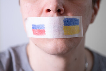 Scotch-taped mouth with the flag of Russia and Ukraine, trying to say.