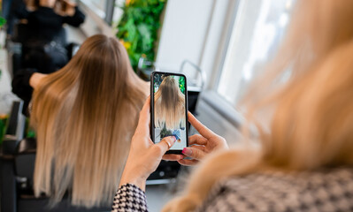 Professional hairdresser taking photo of blonde client's hair extensions for social media showcase