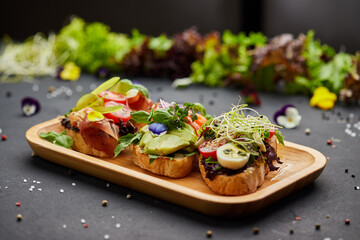 Assorted bruschetta set with salmon, parma and pesto souce. Italian antipasti snacks. Variety mix of small sandwiches on dark background. Photo for restaurant menu