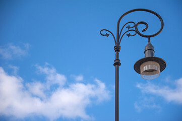 Fototapeta na wymiar Beautiful forged lantern in the old city against the blue sky