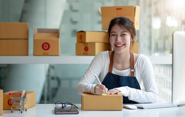 Portrait of Asian young woman working with a box at home the workplace.start-up small business...