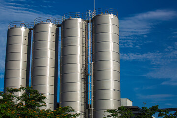 Stainless steel silos in the chemical industry, bulk plastics silo against © chitsanupong