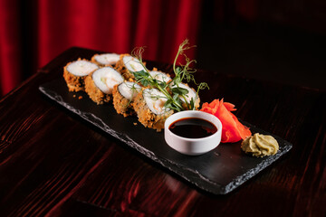 Sushi roll set with ginger and wasabi on black stone.