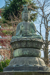 Ancient bronze statue of Guanyin Bodhisattva, sitting in lotus position on the grounds of the oldest Buddhist temple in Japan dedicated to the bodhisattva Kannon, Tokyo, Japan