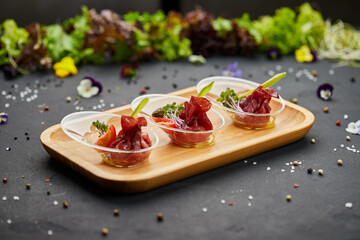 Appetizer from dry cured ham, prosciutto slices on a dark background. Photo for restaurant menu