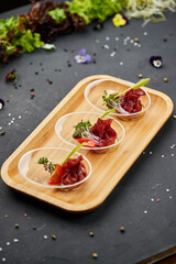 Appetizer from dry cured ham, prosciutto slices on a dark background. Photo for restaurant menu