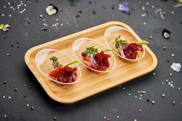 Appetizer from dry cured ham, prosciutto slices on a dark background. Photo for restaurant menu